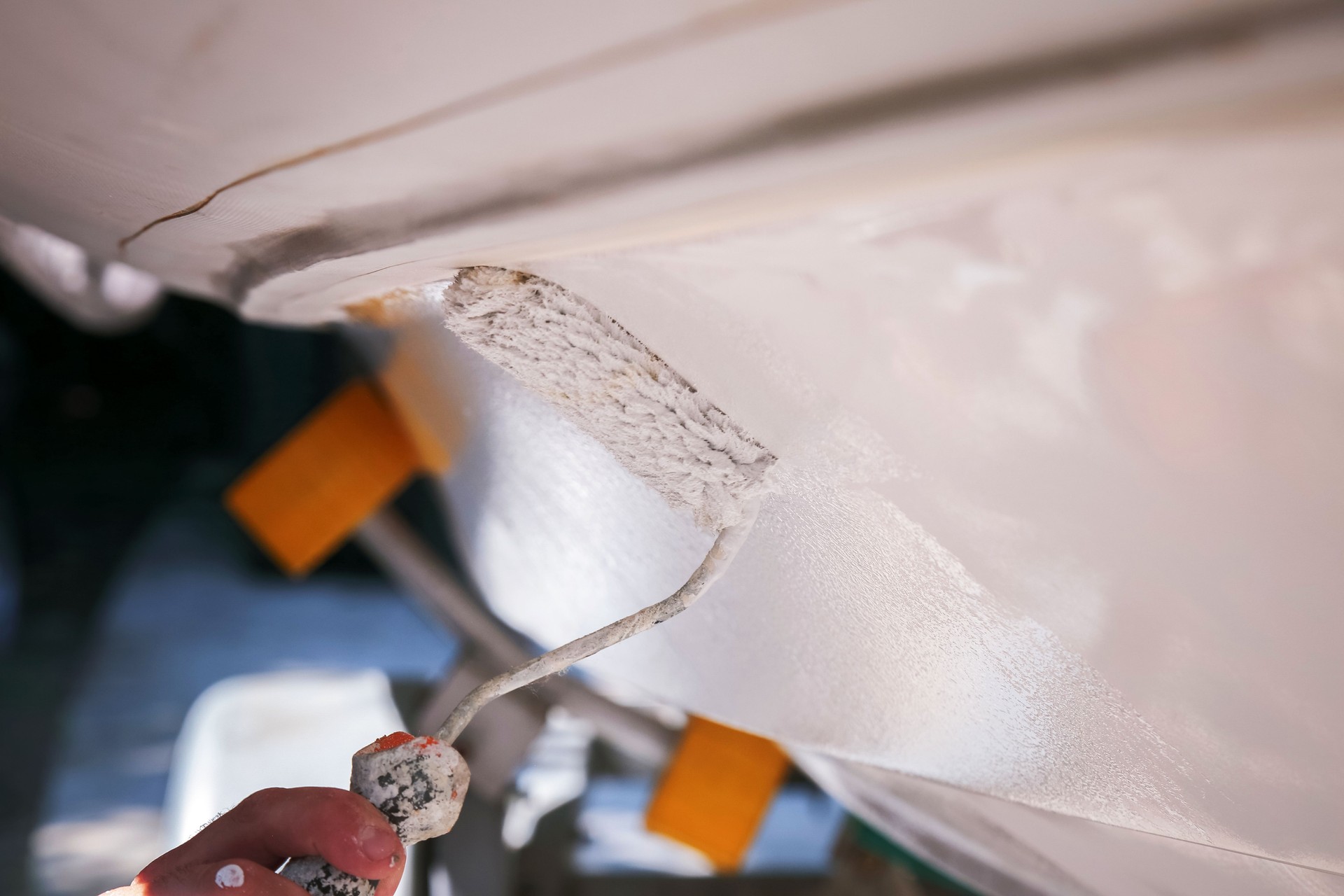 Boat maintenance, applying white toxic paint on boat bottom